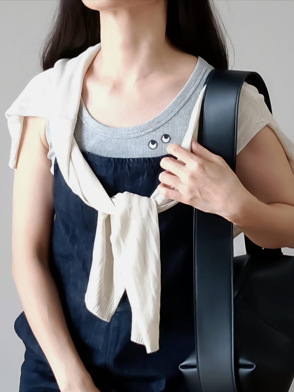 ブラック系のショルダーバッグ、ブラック系のサンダル、グレー系のタンクトップを着用したレディースの夏コーディネートの4枚目の写真