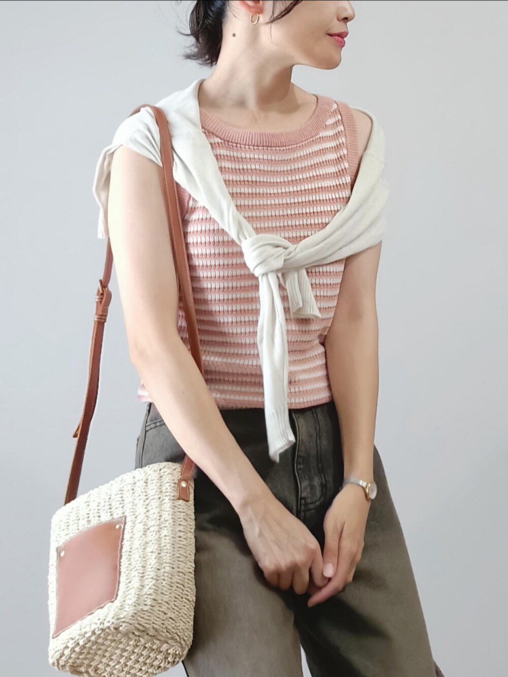 ブラック系のデニムパンツ、ピンク系のタンクトップ、ブラウン系のかごバッグを着用したレディースの夏コーディネートの2枚目の写真