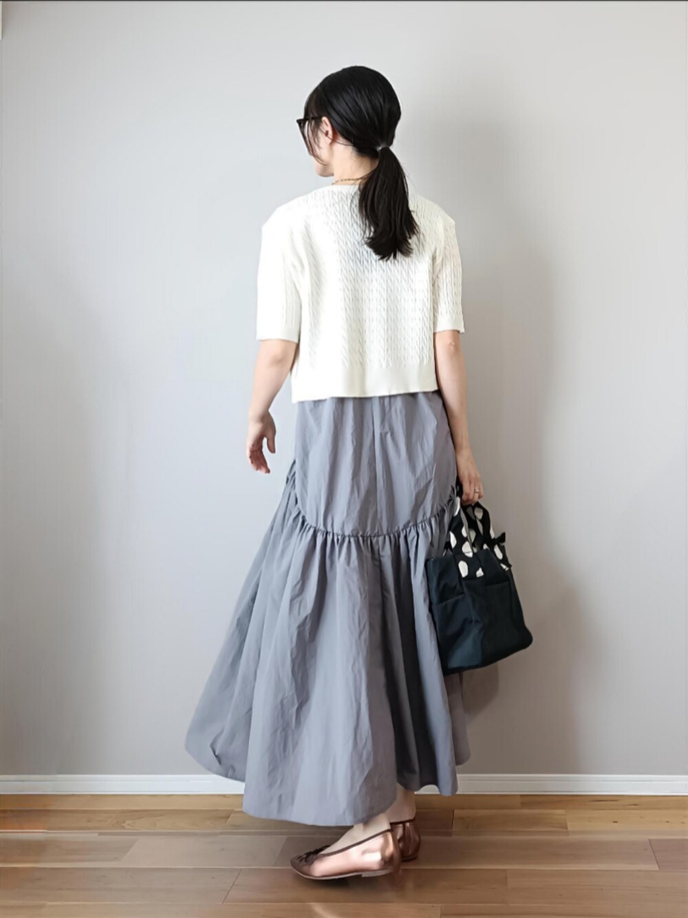 ホワイト系のカーディガン/ボレロ、グレー系のワンピース、ブラック系のハンドバッグを着用したレディースの夏コーディネートの3枚目の写真