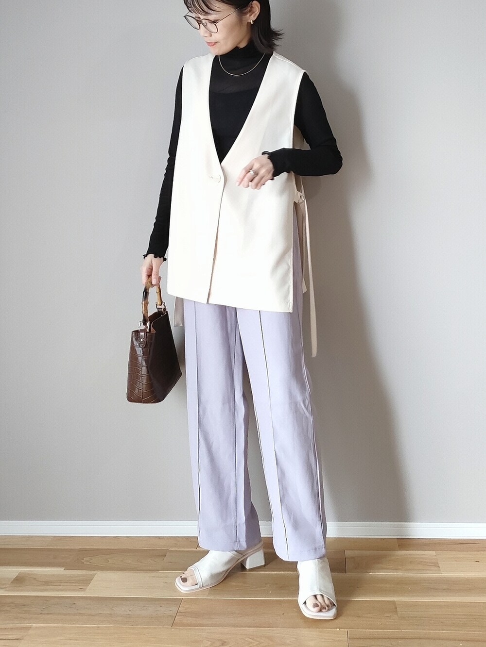 ブラック系のTシャツ/カットソー、ホワイト系のベスト、ホワイト系のサンダルを着用したレディースの春コーディネートの3枚目の写真