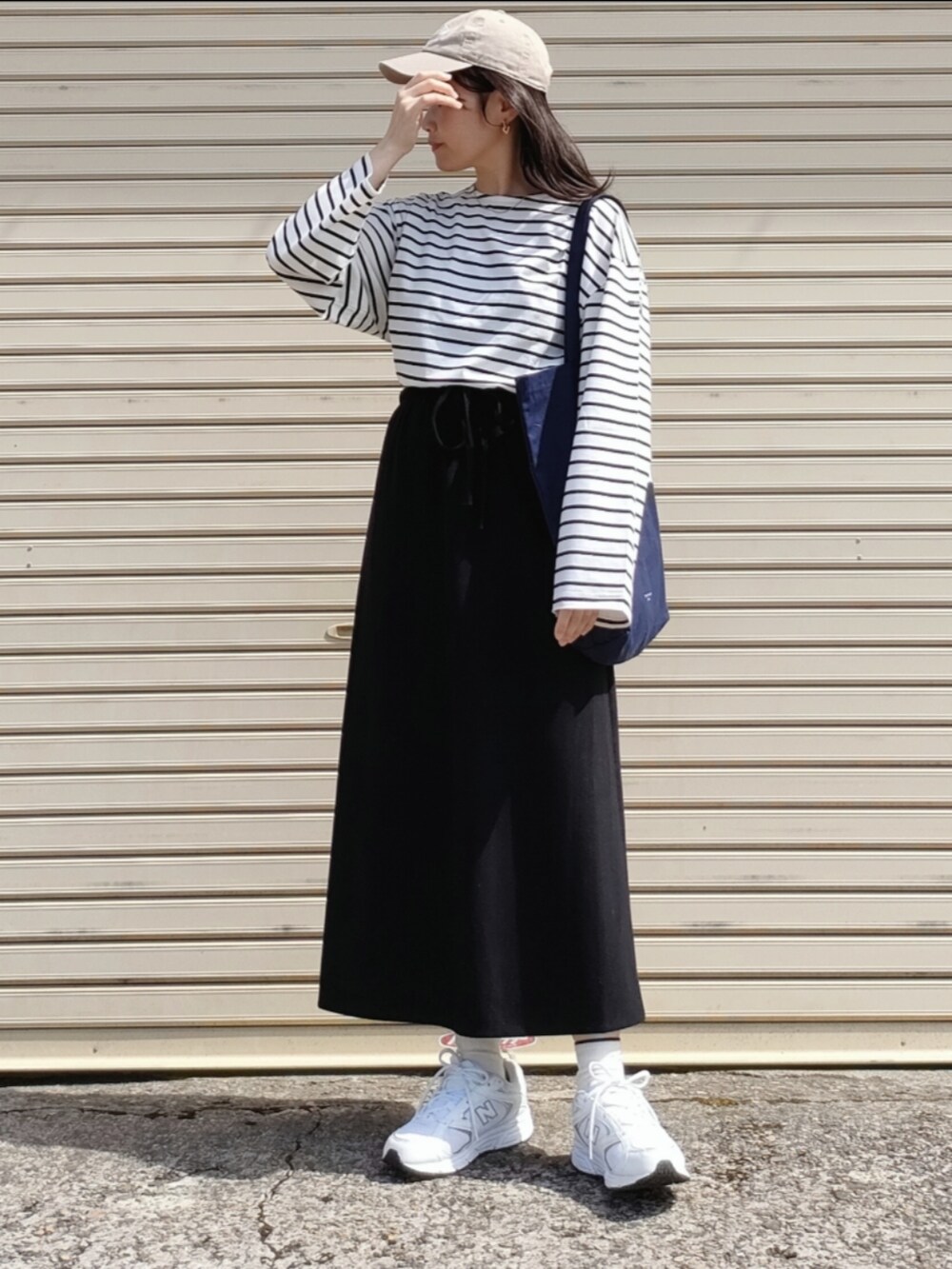 ホワイト系のTシャツ/カットソー、ブラック系のスカート、ブルー系のトートバッグを着用したレディースの春コーディネートの2枚目の写真