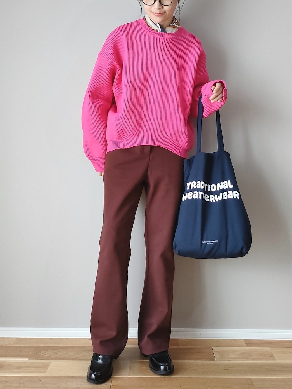 ピンク系のニット/セーター、ブラウン系のスラックス、ブルー系のトートバッグを着用したレディースの秋コーディネートの4枚目の写真