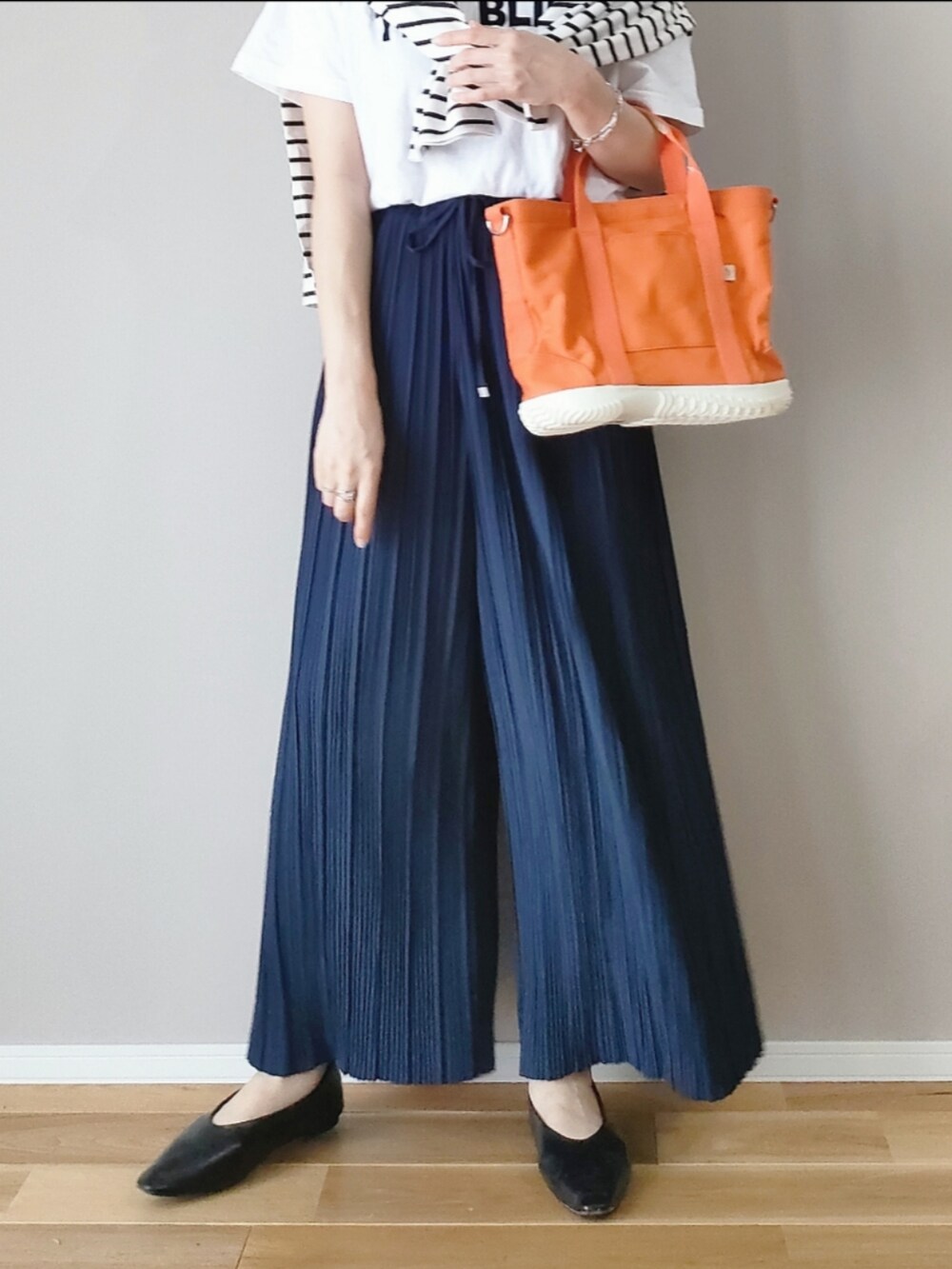 オレンジ系のトートバッグ、ブルー系のその他パンツ、ホワイト系のTシャツ/カットソーを着用したレディースの春コーディネートの3枚目の写真