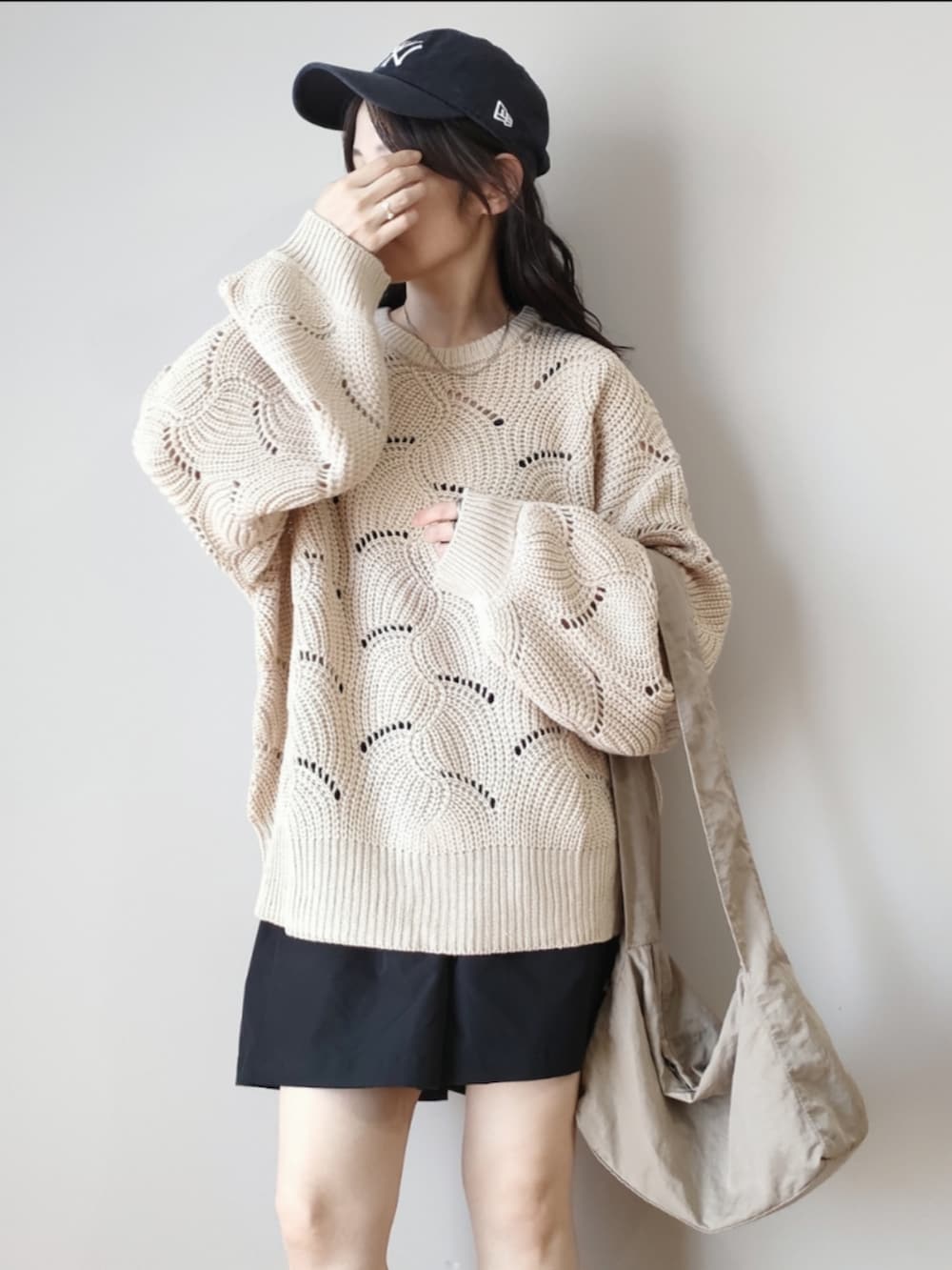 ホワイト系のニット/セーター、ベージュ系のハンドバッグ、ブラック系のブーツを着用したレディースの秋コーディネートの2枚目の写真