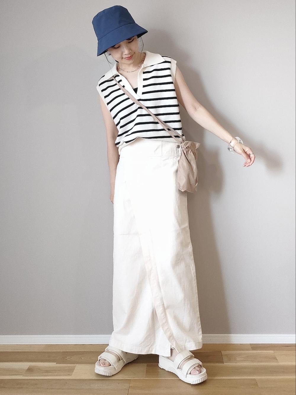 ホワイト系のベスト、ホワイト系のスカート、ベージュ系のショルダーバッグを着用したレディースの夏コーディネートの4枚目の写真