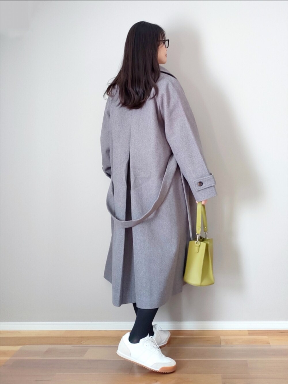グレー系のステンカラーコート、ホワイト系のニット/セーター、ホワイト系のスニーカーを着用したレディースの冬コーディネートの2枚目の写真