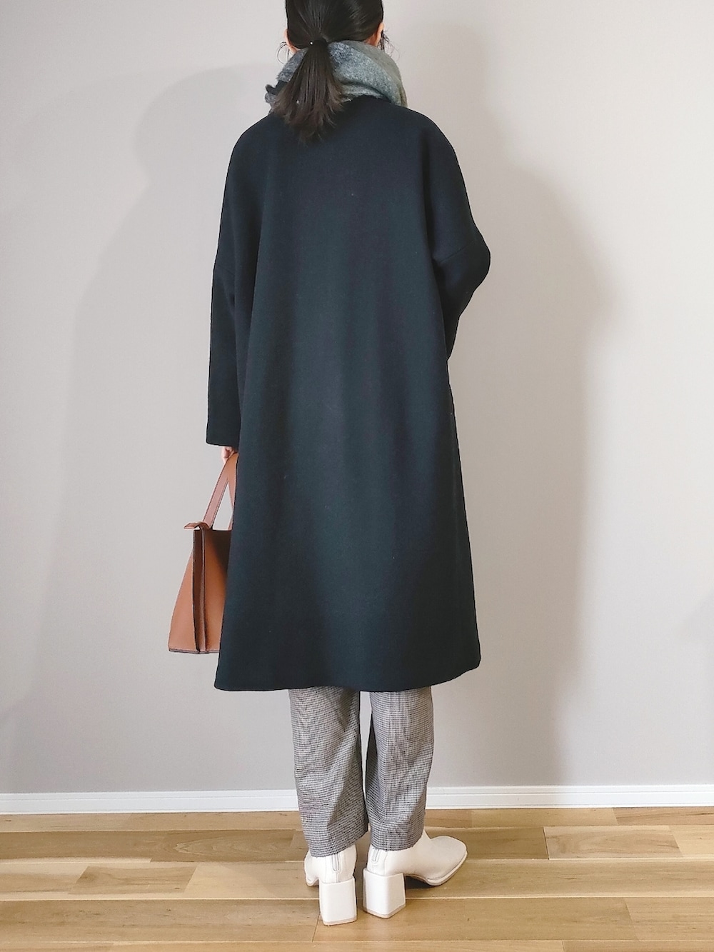 ブラウン系のショルダーバッグ、ブラック系のジャケット/アウター、ホワイト系のブーツを着用したレディースの冬コーディネートの4枚目の写真