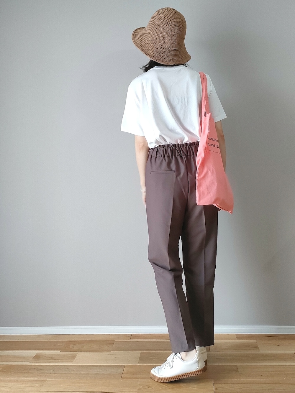 ホワイト系のTシャツ/カットソー、ブラウン系のスラックス、ピンク系のトートバッグを着用したレディースの夏コーディネートの2枚目の写真
