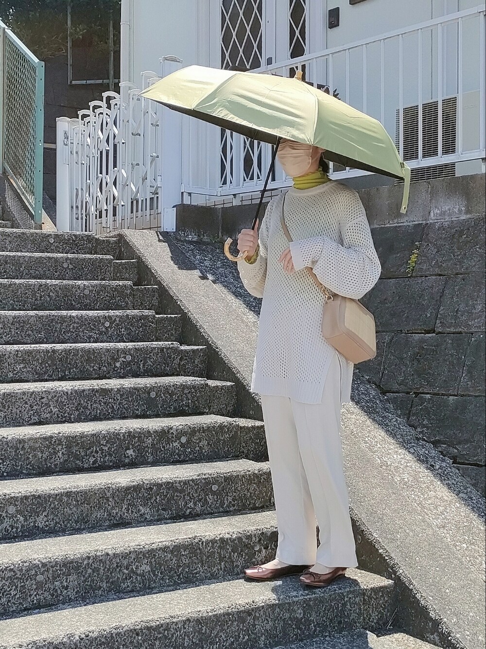 グリーン系のTシャツ/カットソー、ホワイト系のニット/セーター、ゴールド系のバレエシューズを着用したレディースの春コーディネートの2枚目の写真