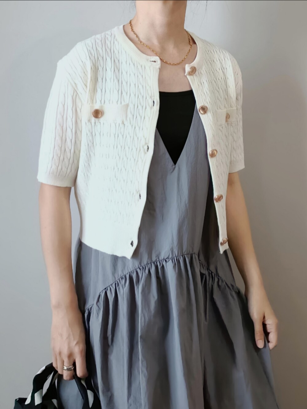 ホワイト系のカーディガン/ボレロ、グレー系のワンピース、ブラック系のハンドバッグを着用したレディースの夏コーディネートの2枚目の写真