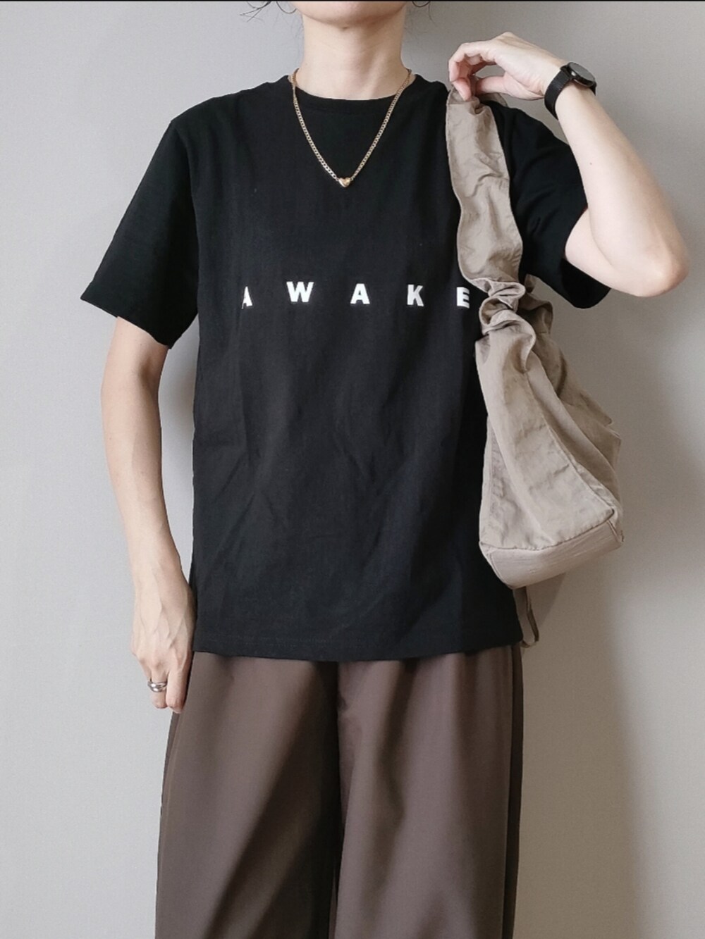 ブラウン系のスラックス、ブラック系のTシャツ/カットソー、ベージュ系のハンドバッグを着用したレディースの秋コーディネートの2枚目の写真