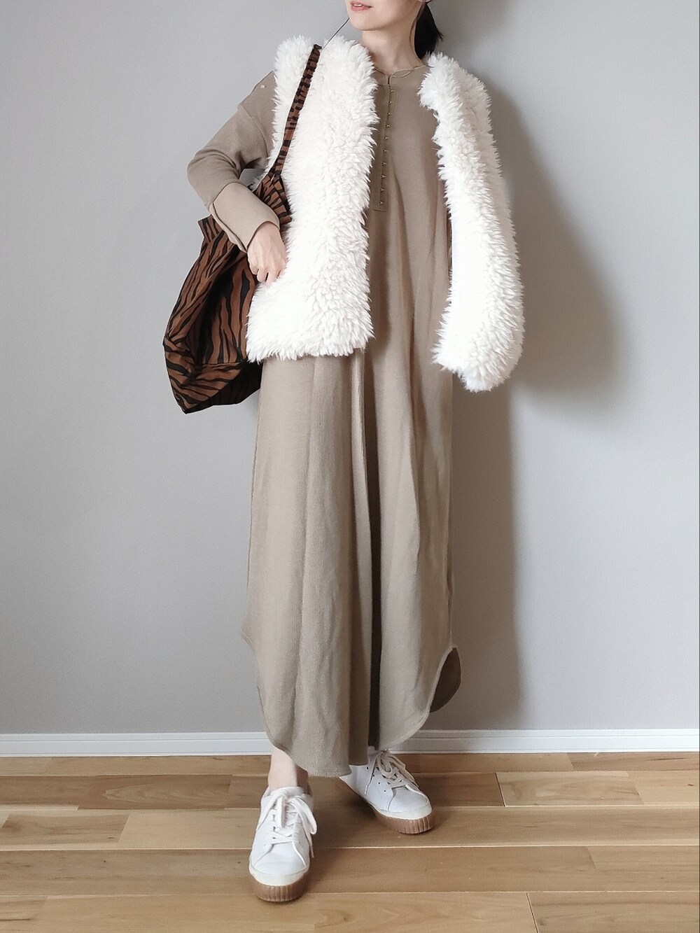 ホワイト系のベスト、ベージュ系のワンピース、ブラウン系のトートバッグを着用したレディースの秋コーディネートの2枚目の写真