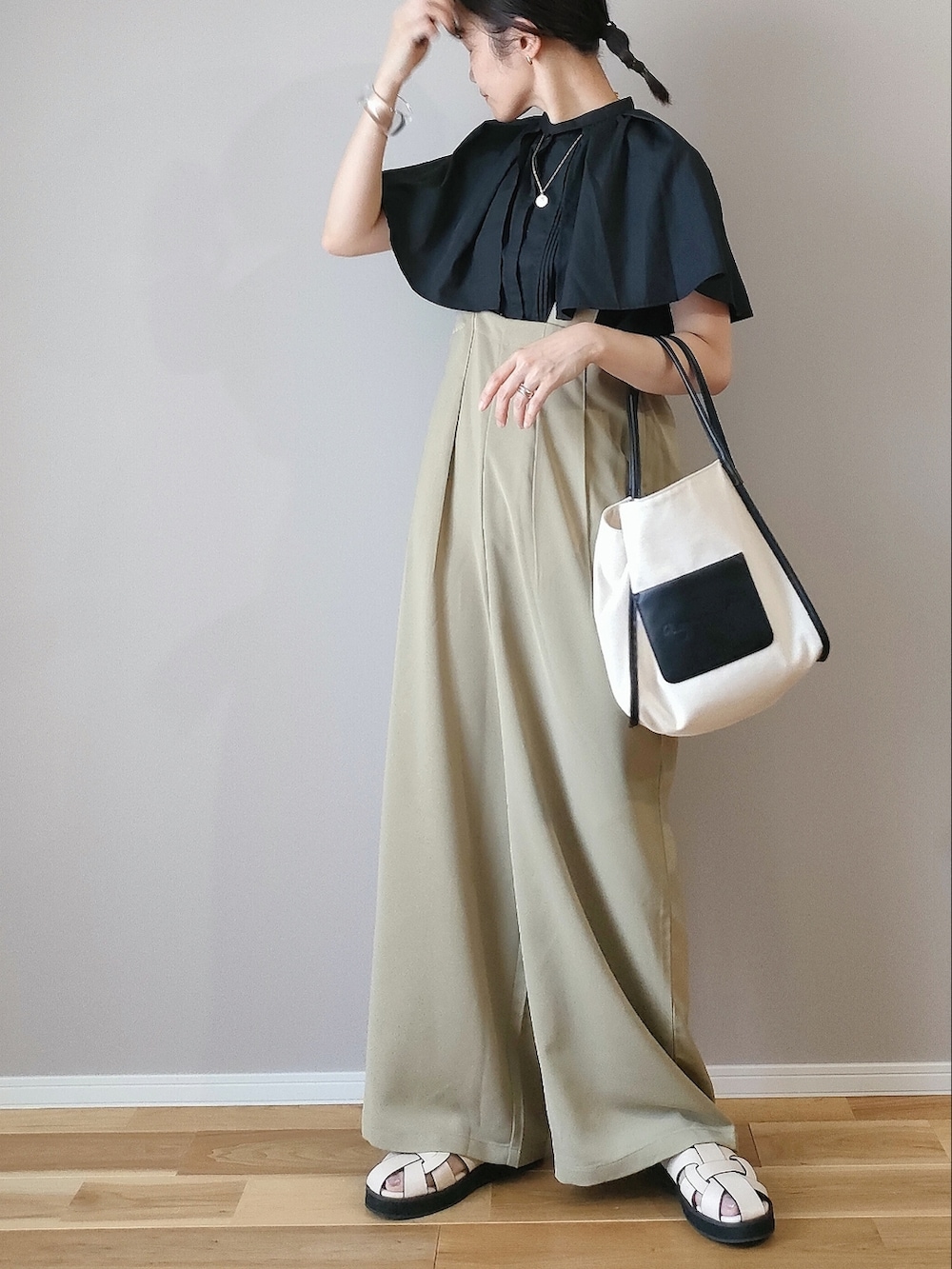 ブラック系のシャツ/ブラウス、グリーン系のサロペット/オーバーオール、ベージュ系のサンダルを着用したレディースの夏コーディネートの2枚目の写真