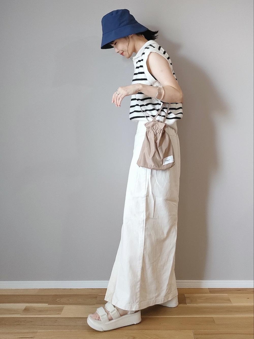 ホワイト系のベスト、ホワイト系のスカート、ベージュ系のショルダーバッグを着用したレディースの夏コーディネートの2枚目の写真