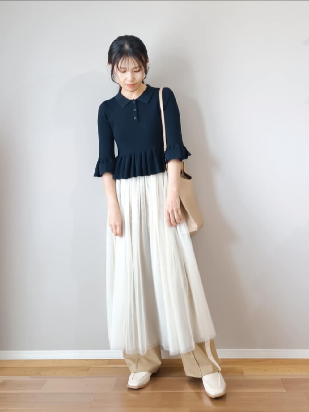 ブルー系のニット/セーター、ベージュ系のパンツ、ホワイト系のスカートを着用したレディースの春コーディネートの2枚目の写真