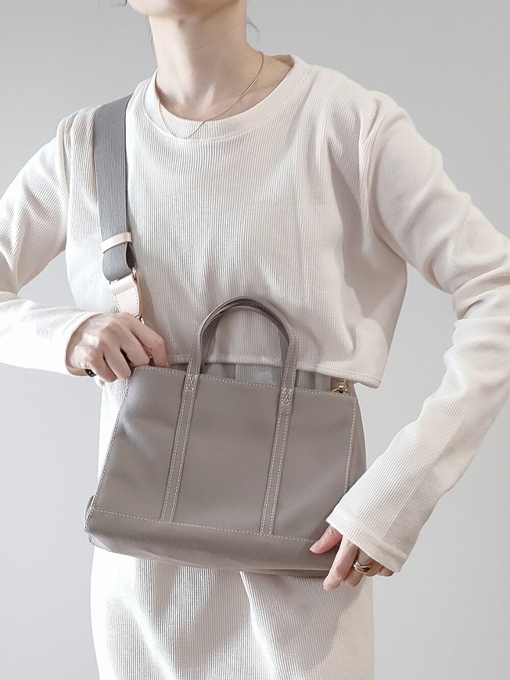 ホワイト系のワンピース、グレー系のハンドバッグ、ブラック系のスニーカーを着用したレディースの春コーディネートの4枚目の写真