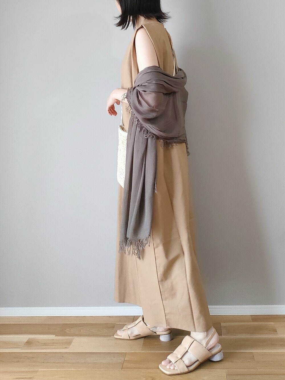 イエロー系のワンピース、ベージュ系のサンダル、ブラウン系のストール/ショールを着用したレディースの夏コーディネートの2枚目の写真