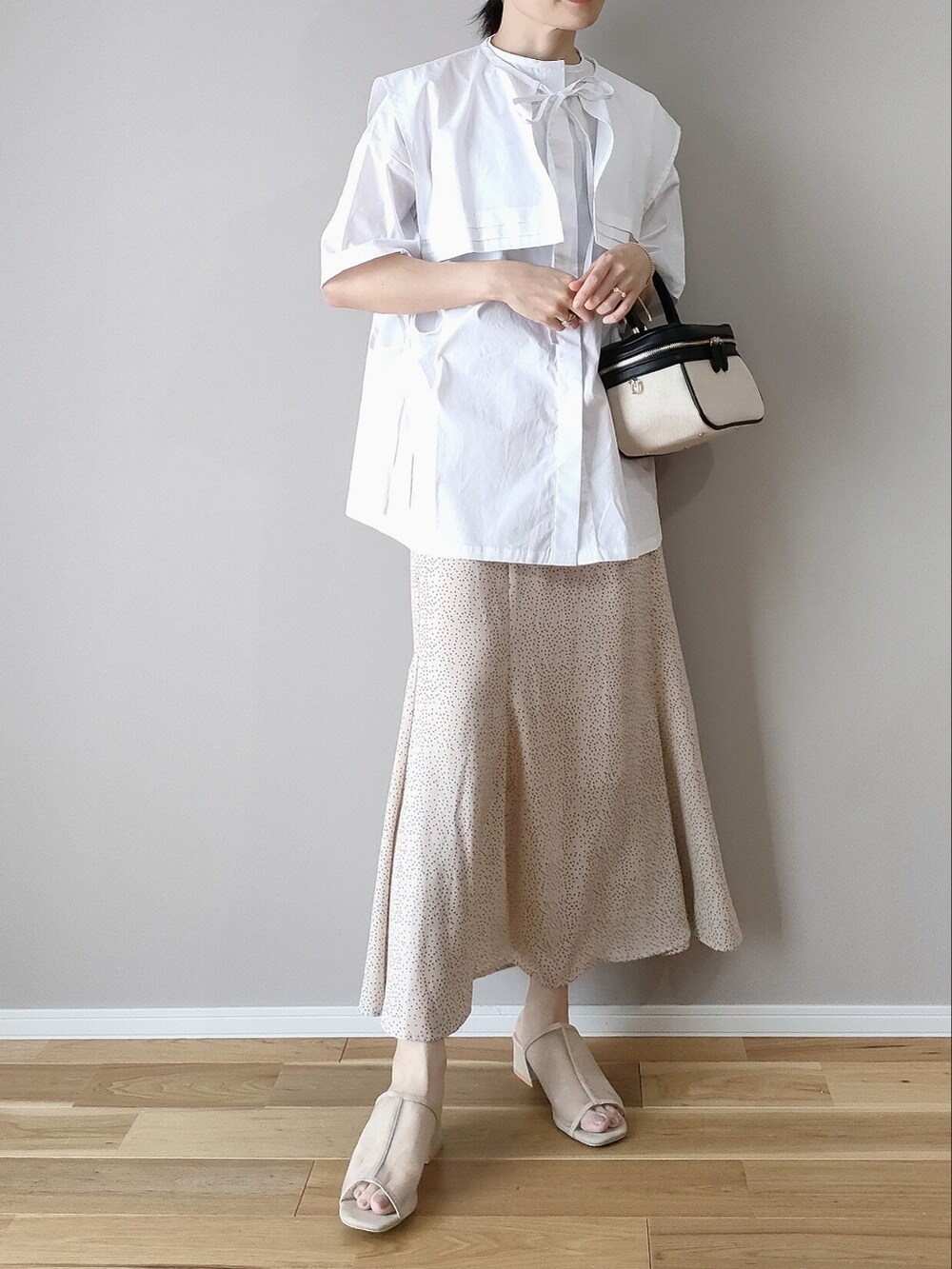 ホワイト系のシャツ/ブラウス、ホワイト系のスカート、ブラック系のハンドバッグを着用したレディースの夏コーディネートの2枚目の写真