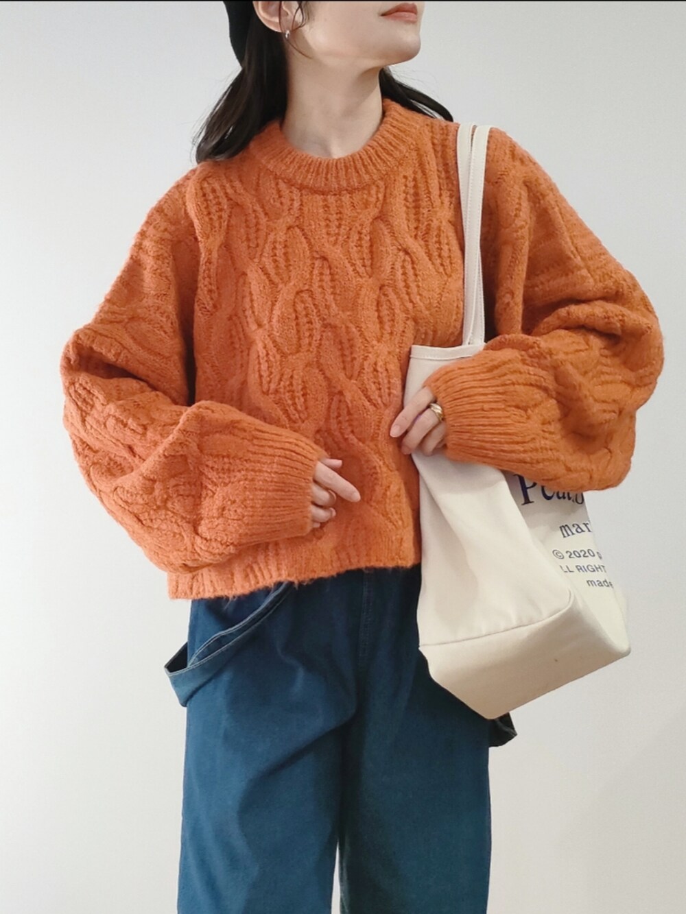 オレンジ系のニット/セーター、ブラック系のブーツ、ブルー系のサロペット/オーバーオールを着用したレディースの冬コーディネートの2枚目の写真