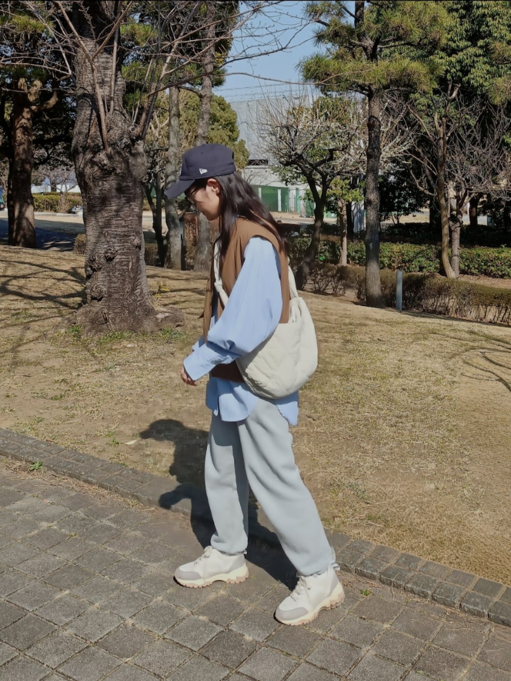 ブラウン系のベスト、ブルー系のシャツ/ブラウス、グレー系のスウェットパンツを着用したレディースの春コーディネートの2枚目の写真