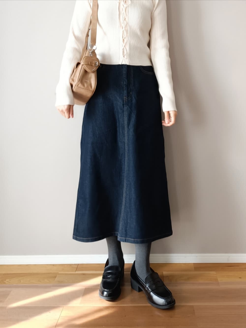 ブルー系のデニムスカート、ホワイト系のニット/セーター、ブラック系のローファーを着用したレディースの冬コーディネートの2枚目の写真