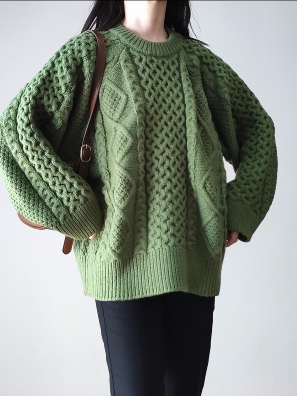 グリーン系のニット/セーター、ブラウン系のショルダーバッグ、グレー系のスニーカーを着用したレディースの秋コーディネートの2枚目の写真