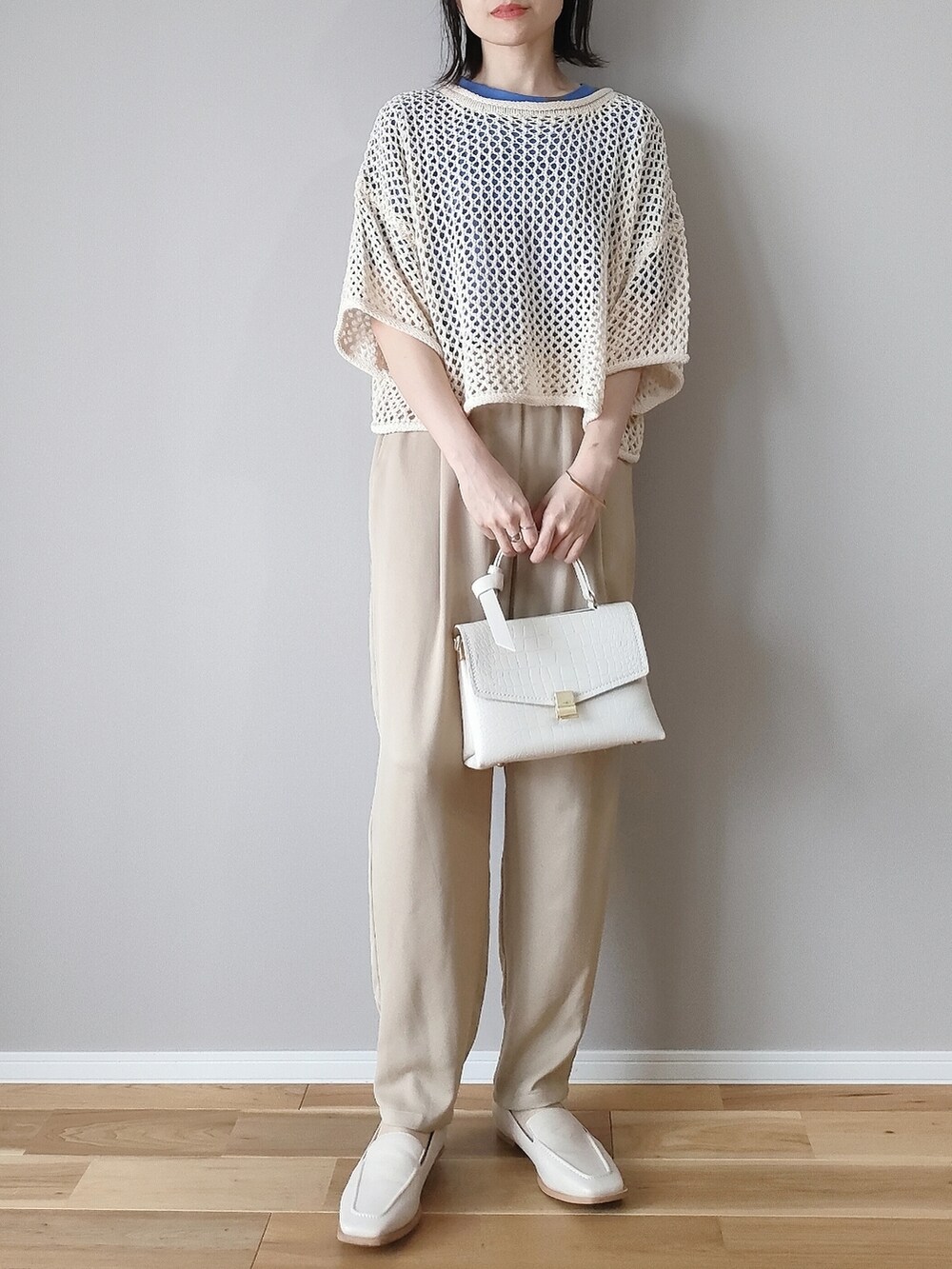 ホワイト系のニット/セーター、ブルー系のTシャツ/カットソー、ホワイト系のショルダーバッグを着用したレディースの春コーディネートの2枚目の写真