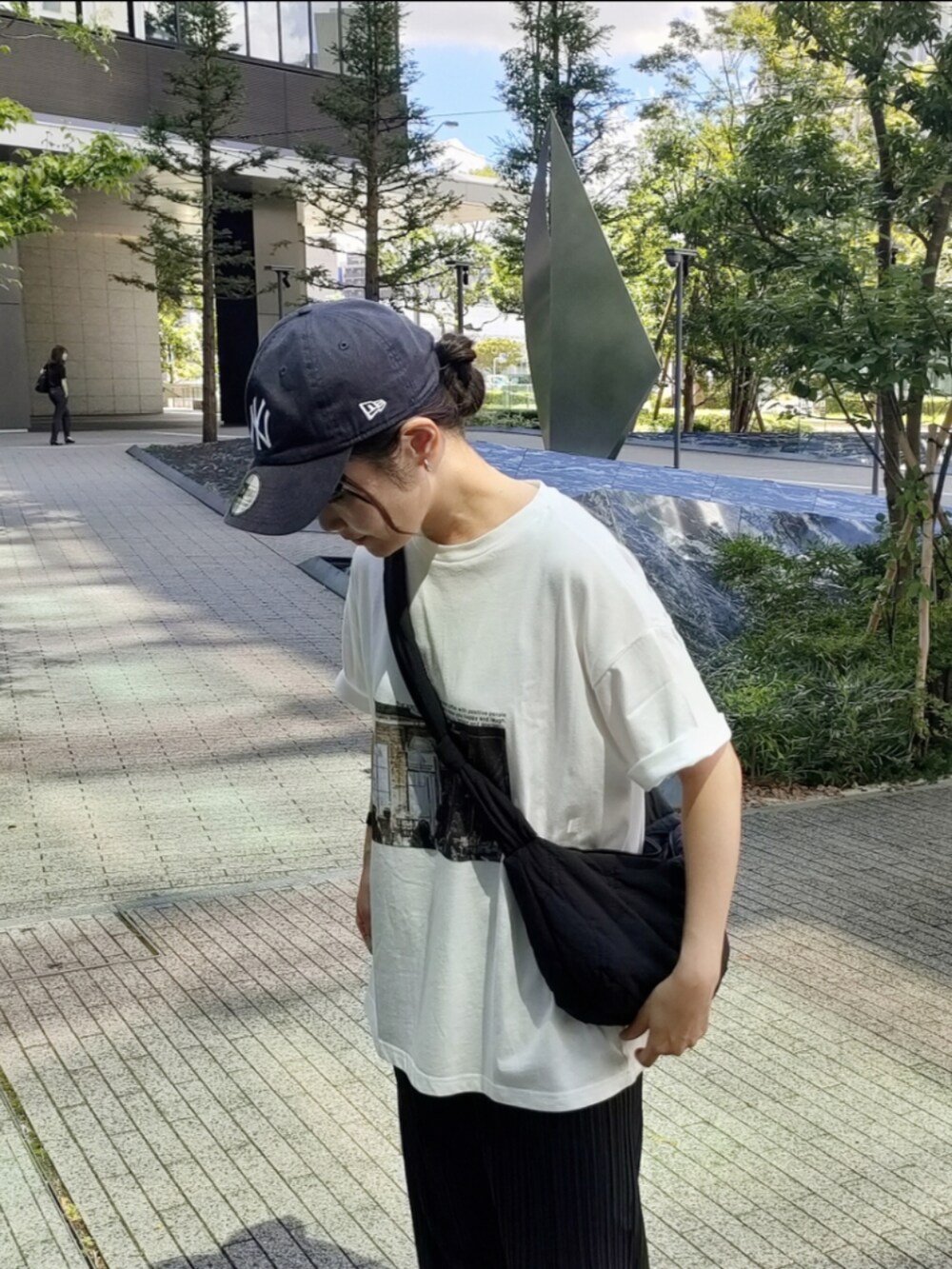 ホワイト系のTシャツ/カットソー、ブラック系のサンダル、ブラック系のショルダーバッグを着用したレディースの秋コーディネートの2枚目の写真