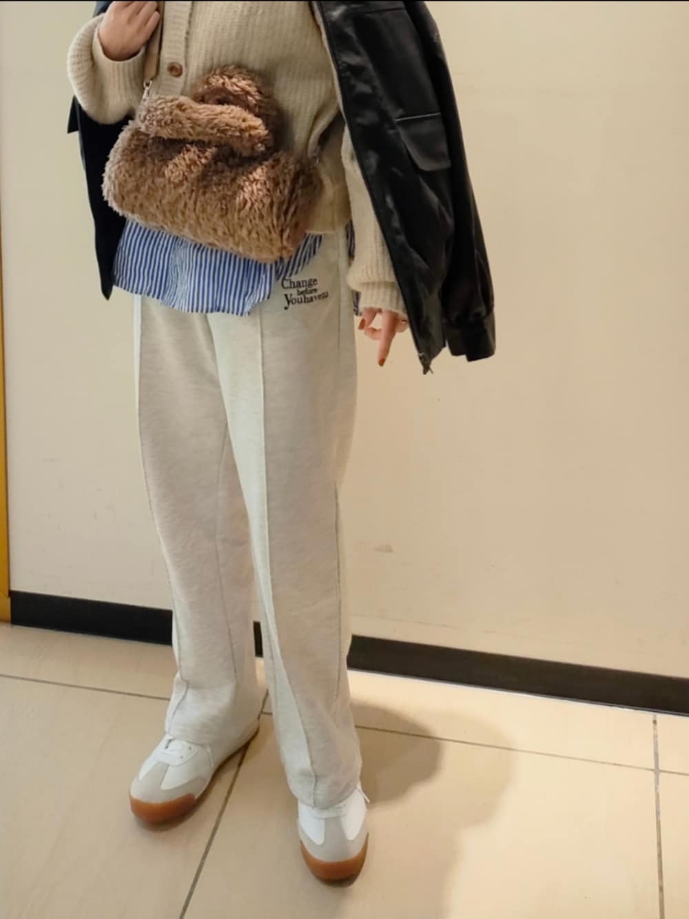 ベージュ系のスウェットパンツ、ブラック系のブルゾン、ホワイト系のカーディガン/ボレロを着用したレディースの秋コーディネートの4枚目の写真