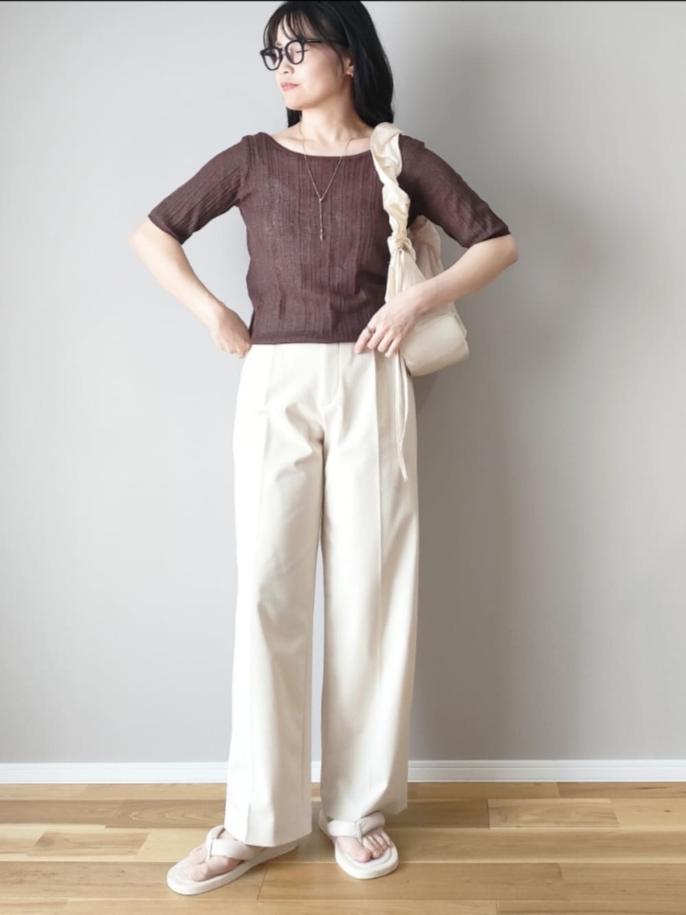 ブラウン系のニット/セーター、ホワイト系のハンドバッグ、ホワイト系のパンツを着用したレディースの夏コーディネートの2枚目の写真