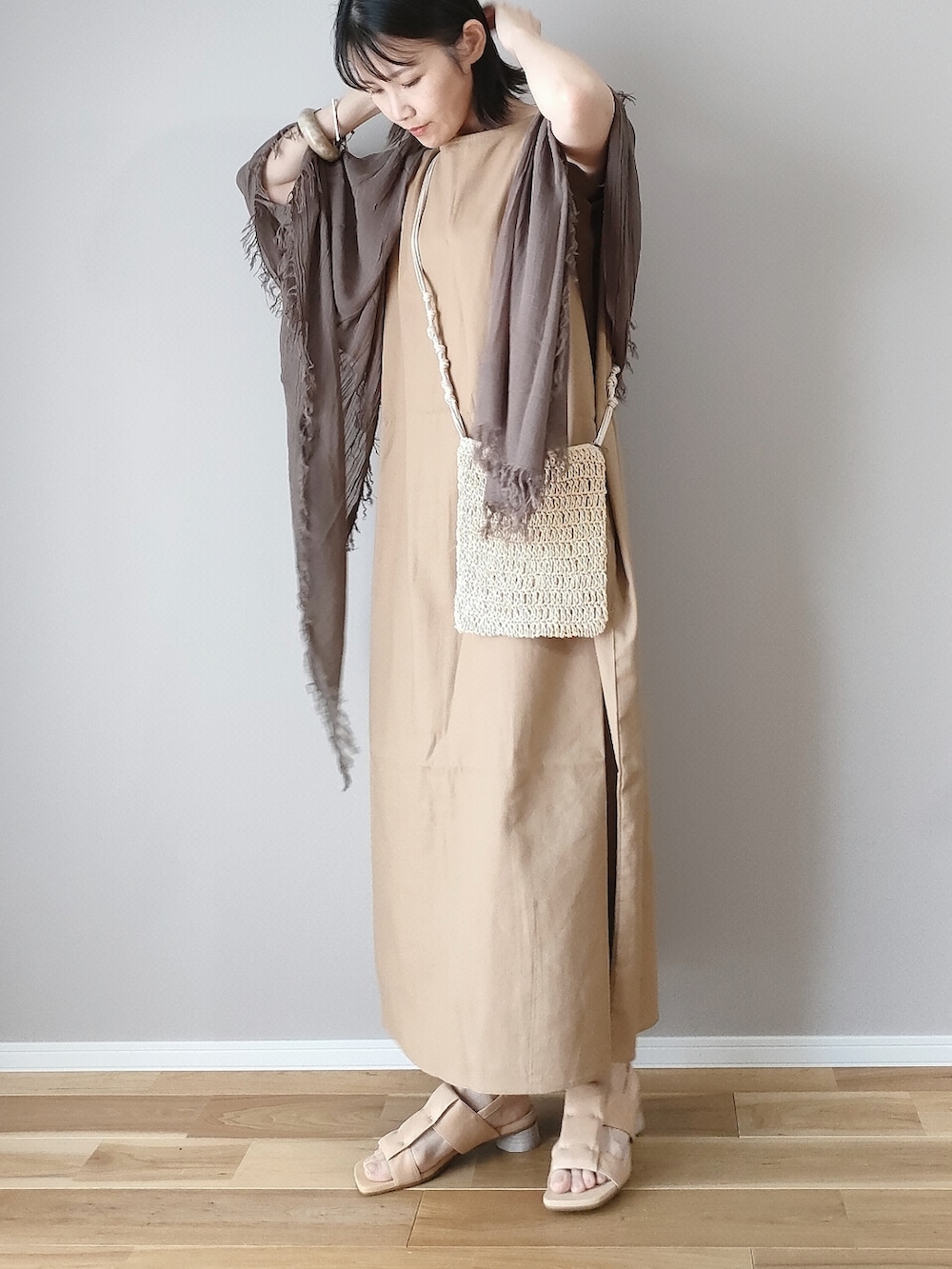 イエロー系のワンピース、ベージュ系のサンダル、ブラウン系のストール/ショールを着用したレディースの夏コーディネートの3枚目の写真