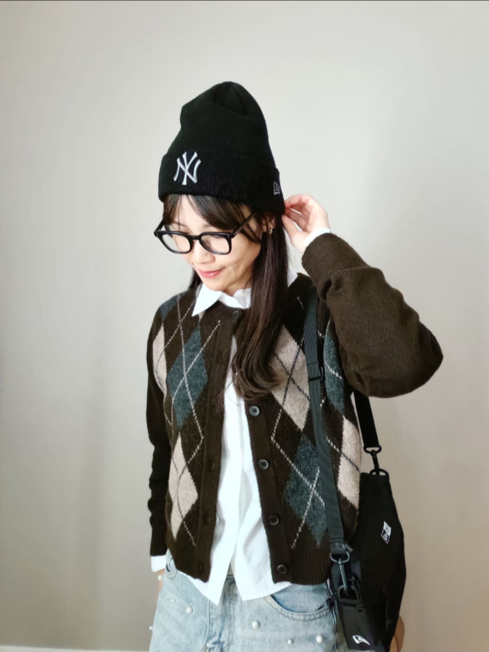 ブルー系のデニムパンツ、ブラック系のショルダーバッグ、ブラウン系のカーディガン/ボレロを着用したレディースの冬コーディネートの2枚目の写真