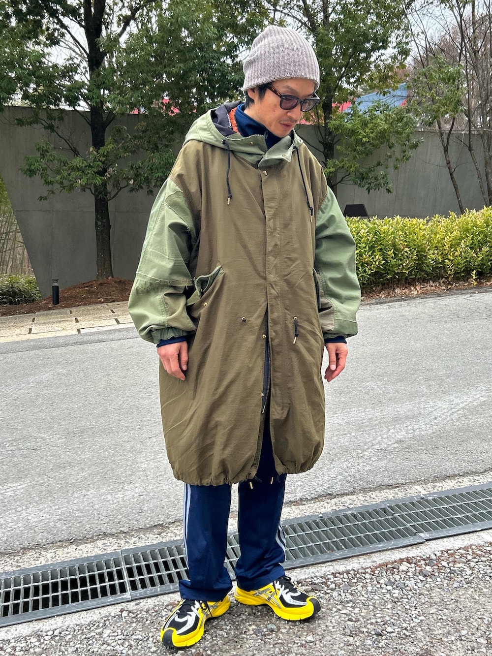 オレンジ系のベスト、グリーン系のモッズコート、ブルー系のスウェットパンツを着用したメンズの春コーディネートの2枚目の写真