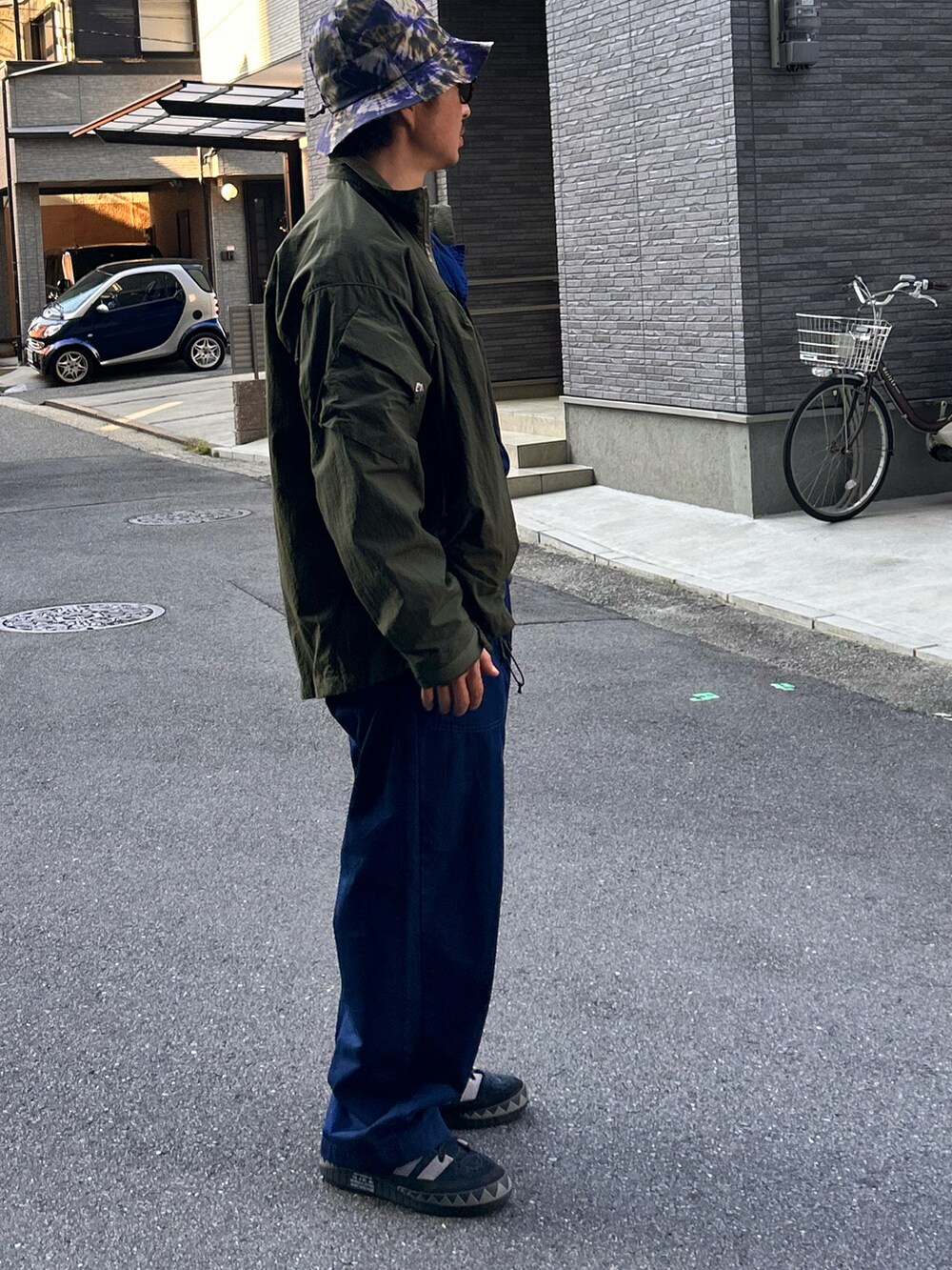 「春コーデ、オールインワン、つなぎ、ジャンプスーツ、BBQ、アウトドアスタイル、ミリタリー、タイダイ柄、バケットハット、ゆるコーデ」｜「CMF OUTDOOR GARMENTのCOMFY OUTDOOR GARMENT/コンフィ― アウトドア ガーメンツ SLING SHOT/スリングショット（ブルゾン、グリーン系）」を使った、yosukeさん（メンズ・168cm）の春コーディネートの2枚目の写真