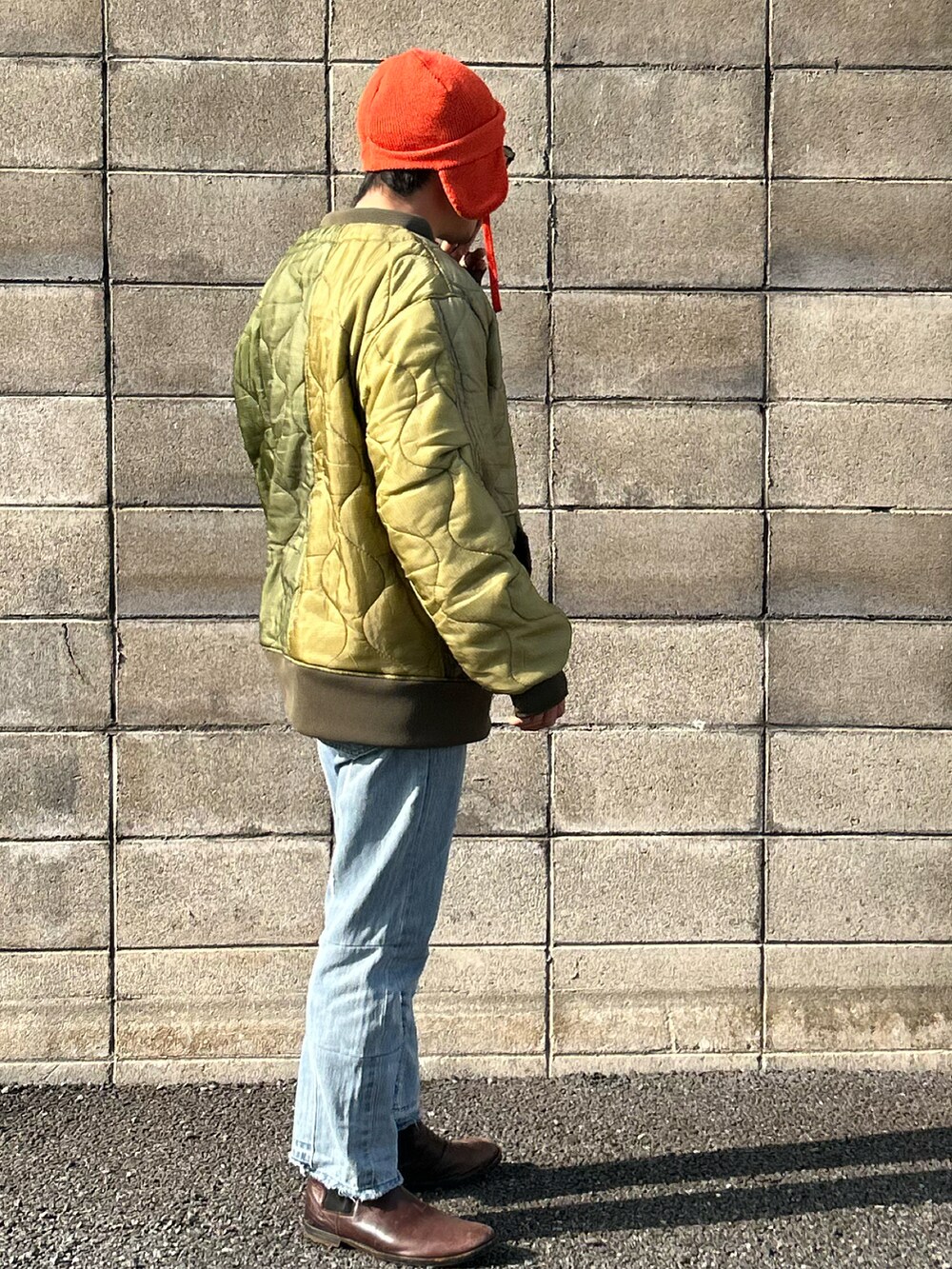 ホワイト系のスウェット、グリーン系のミリタリージャケット、ブルー系のデニムパンツを着用したメンズの冬コーディネートの4枚目の写真