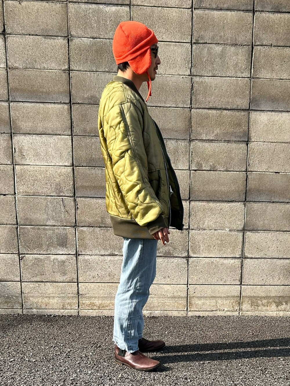 ホワイト系のスウェット、グリーン系のミリタリージャケット、ブルー系のデニムパンツを着用したメンズの冬コーディネートの3枚目の写真