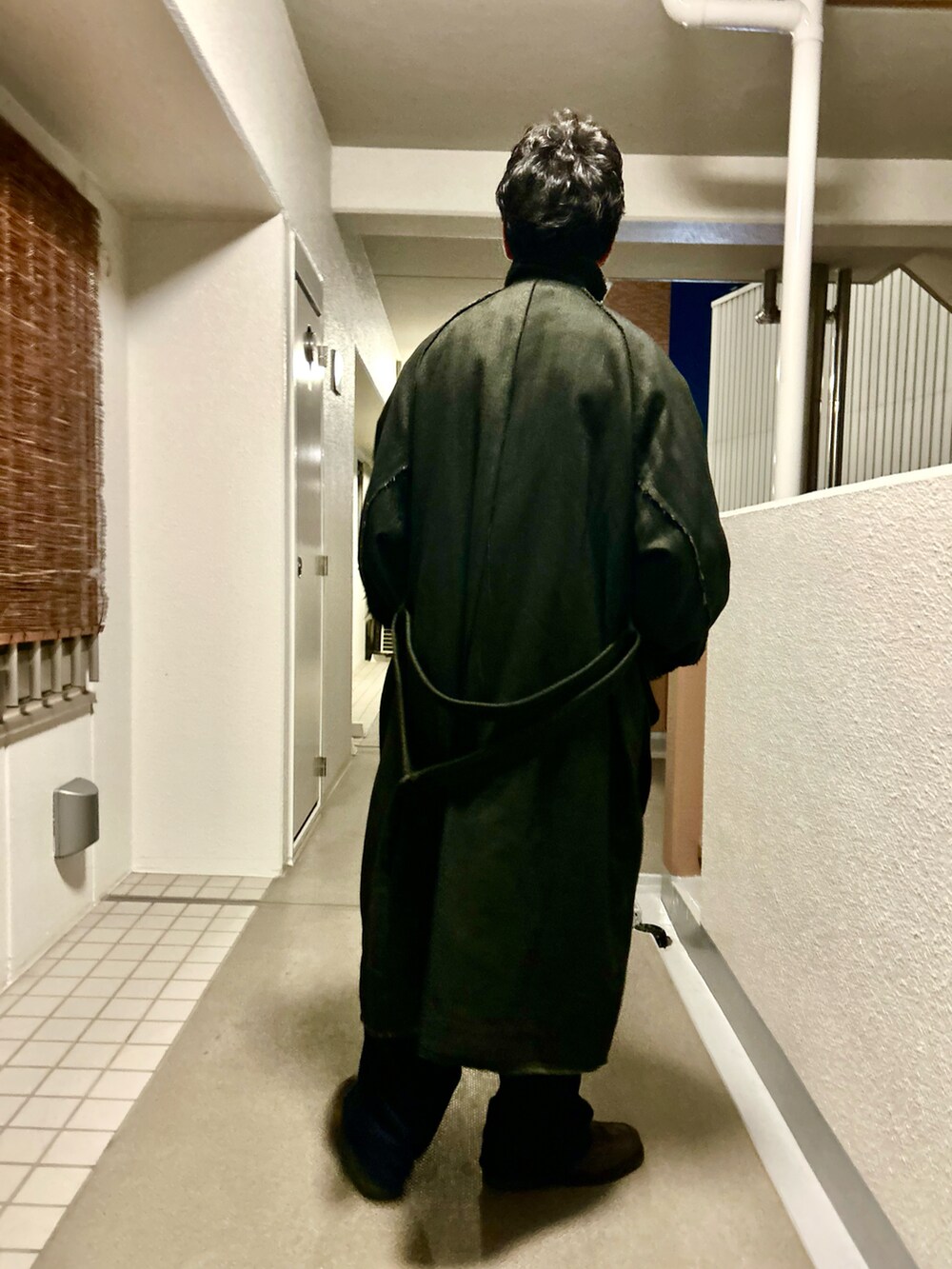 ブラック系のテーラードジャケット、ブラック系のダッフルコート、ブルー系のパンツを着用したメンズの冬コーディネートの4枚目の写真