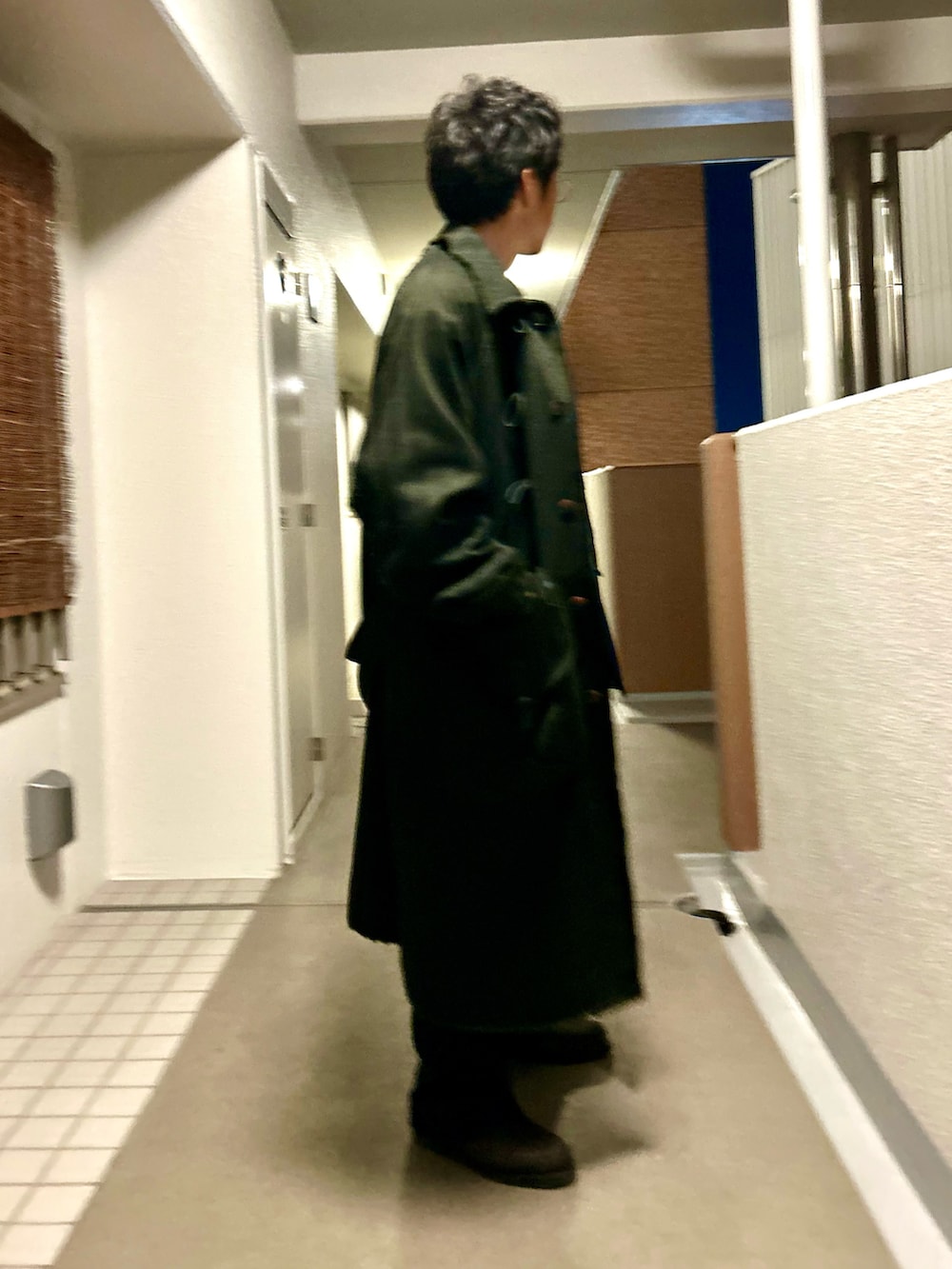 ブラック系のテーラードジャケット、ブラック系のダッフルコート、ブルー系のパンツを着用したメンズの冬コーディネートの2枚目の写真