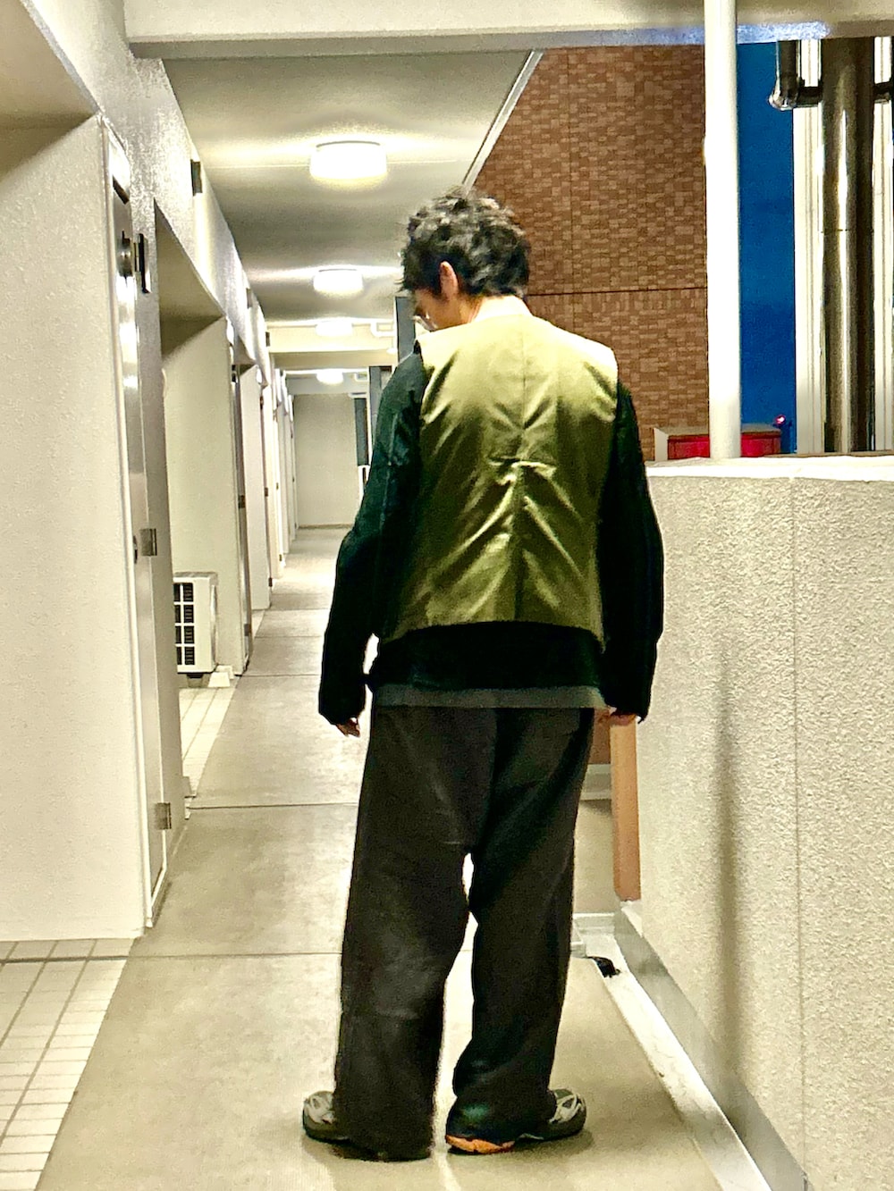 グリーン系のベスト、グレー系のその他パンツ、グレー系のスニーカーを着用したメンズの秋コーディネートの3枚目の写真