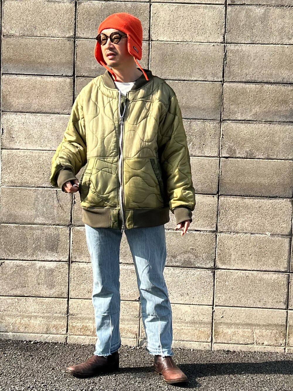 ホワイト系のスウェット、グリーン系のミリタリージャケット、ブルー系のデニムパンツを着用したメンズの冬コーディネートの2枚目の写真