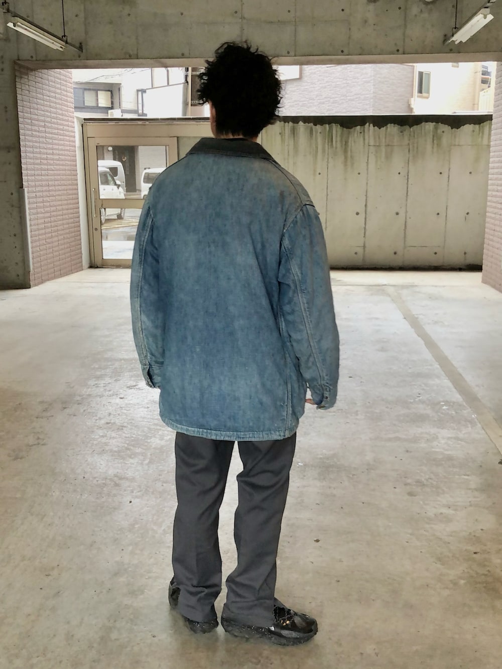 ブルー系のカバーオール、グレー系のチノパンツ、ブラック系のスニーカーを着用したメンズの春コーディネートの4枚目の写真