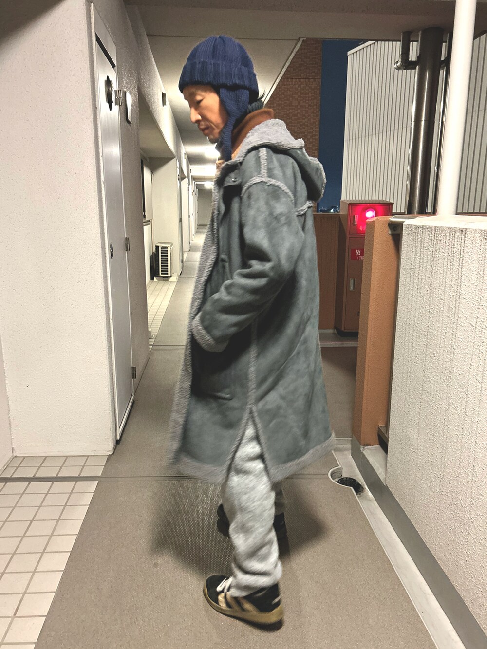 ベージュ系のベスト、グレー系のステンカラーコート、グレー系のその他パンツを着用したメンズの冬コーディネートの2枚目の写真