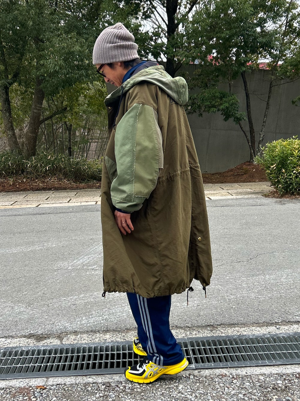 オレンジ系のベスト、グリーン系のモッズコート、ブルー系のスウェットパンツを着用したメンズの春コーディネートの3枚目の写真