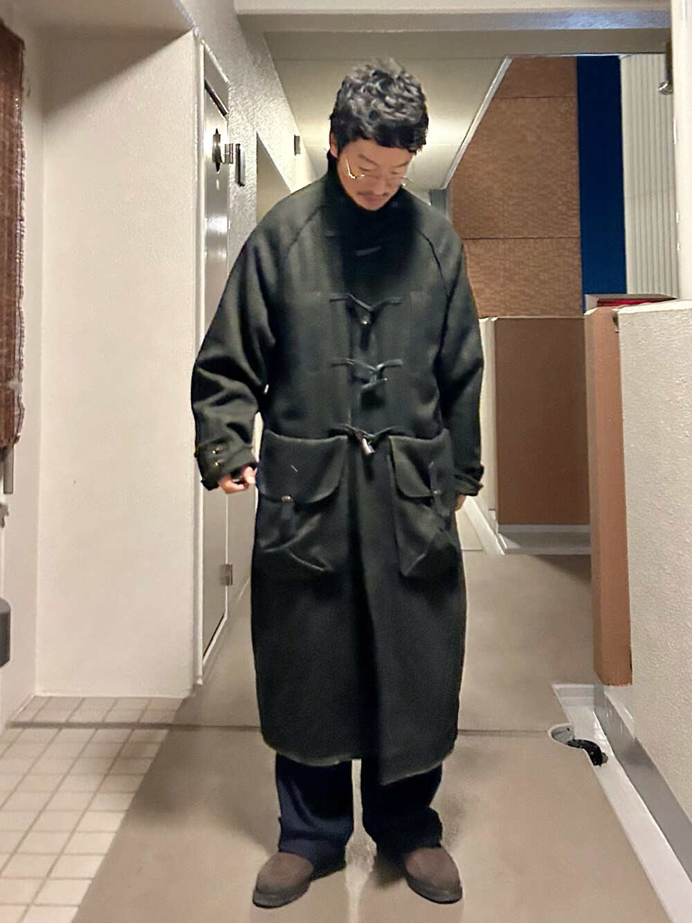 ブラック系のテーラードジャケット、ブラック系のダッフルコート、ブルー系のパンツを着用したメンズの冬コーディネートの3枚目の写真