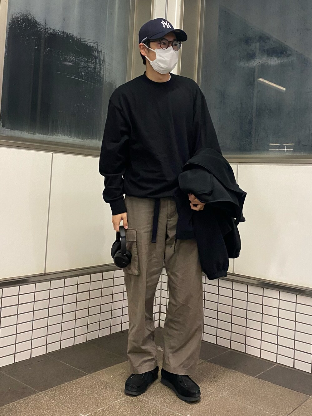 グリーン系のカーゴパンツ、ブラック系のブーツ、ブラック系のブルゾンを着用したメンズの春コーディネートの3枚目の写真