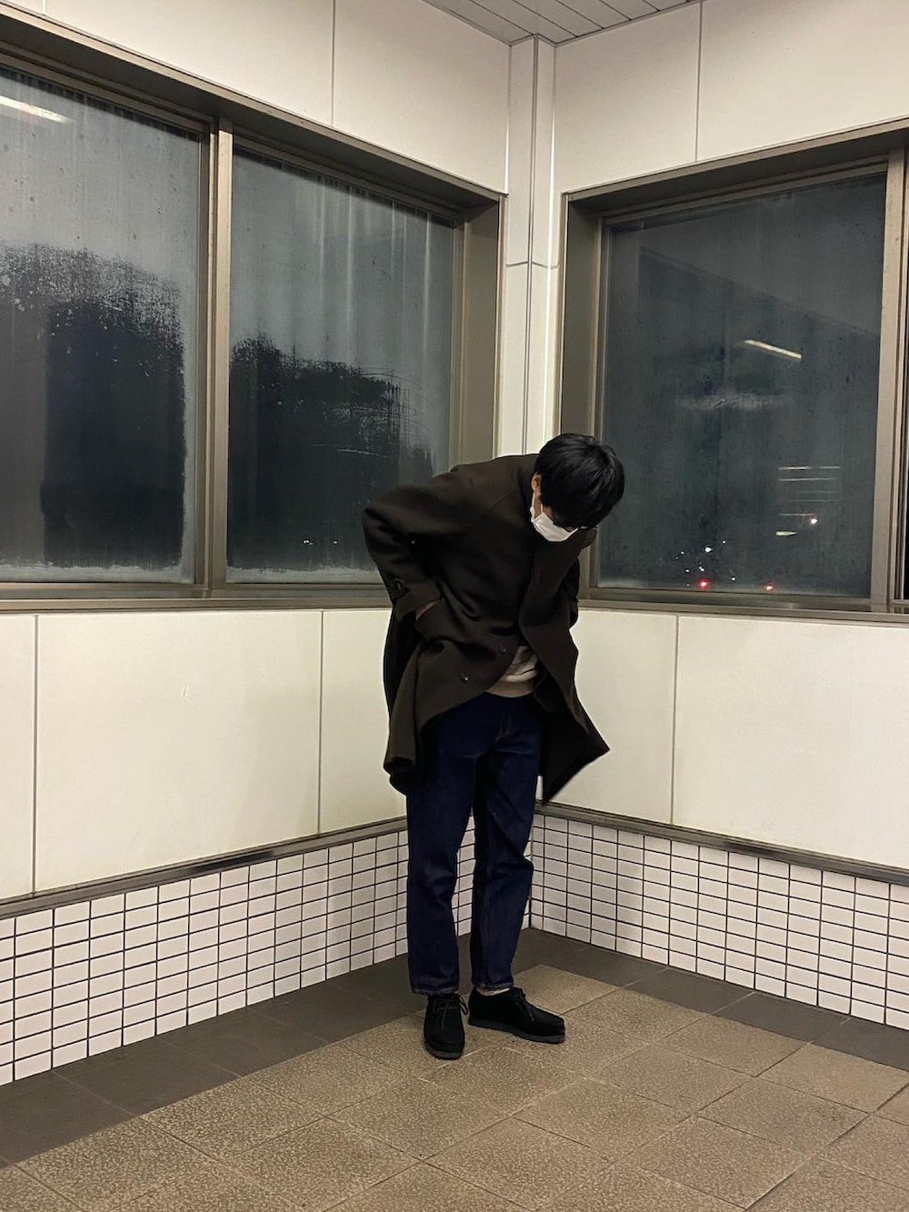 ブラウン系のステンカラーコート、ブルー系のデニムパンツ、ブラック系のブーツを着用したメンズの冬コーディネートの2枚目の写真