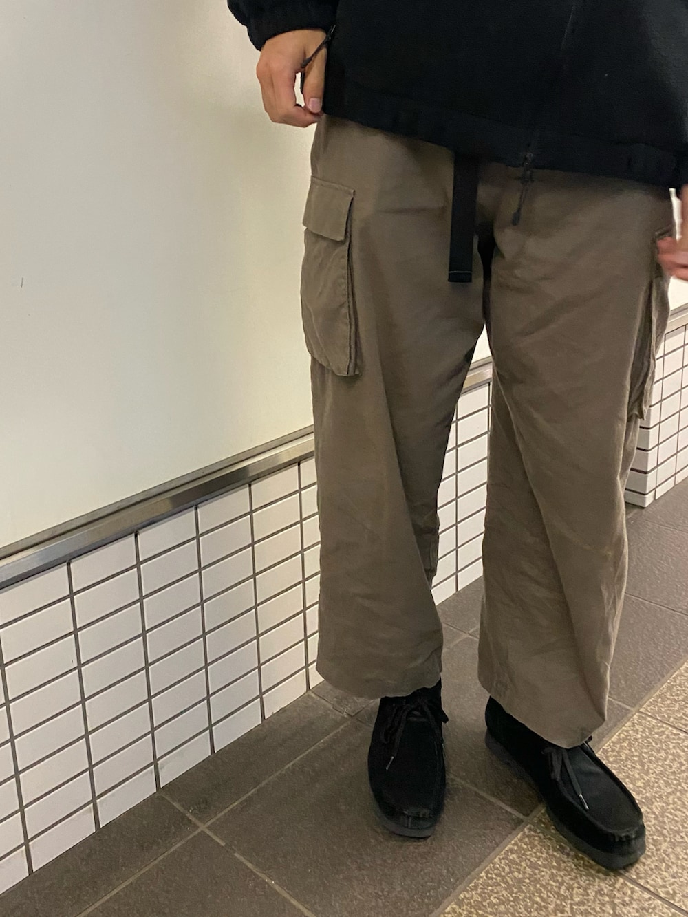 グリーン系のカーゴパンツ、ブラック系のブーツ、ブラック系のブルゾンを着用したメンズの春コーディネートの4枚目の写真