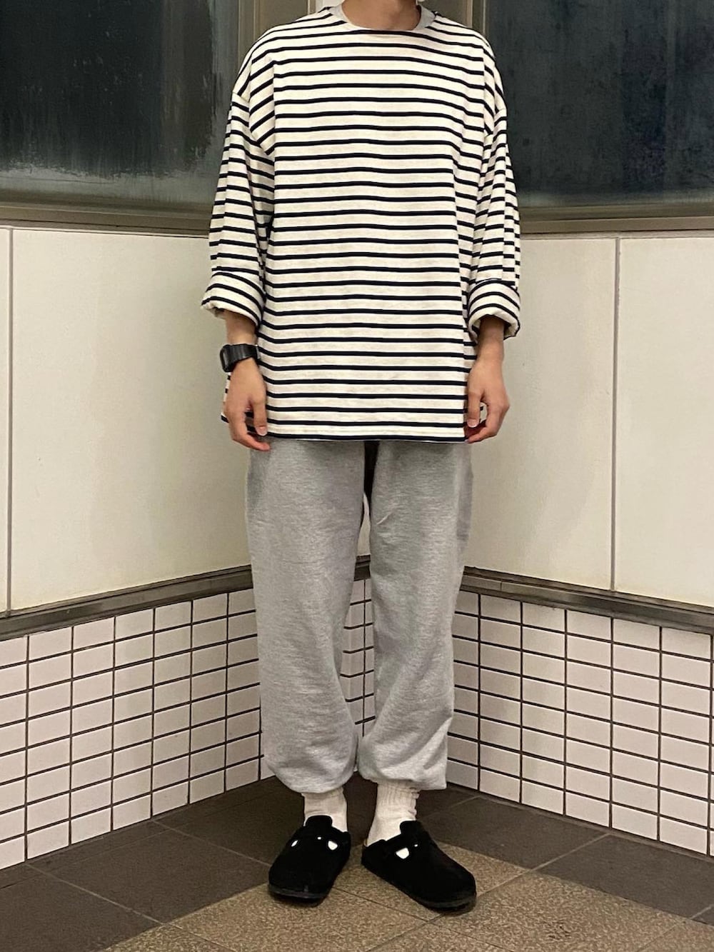 グレー系のスウェットパンツ、ブラック系のサンダル、ブラック系のTシャツ/カットソーを着用したメンズの春コーディネートの2枚目の写真