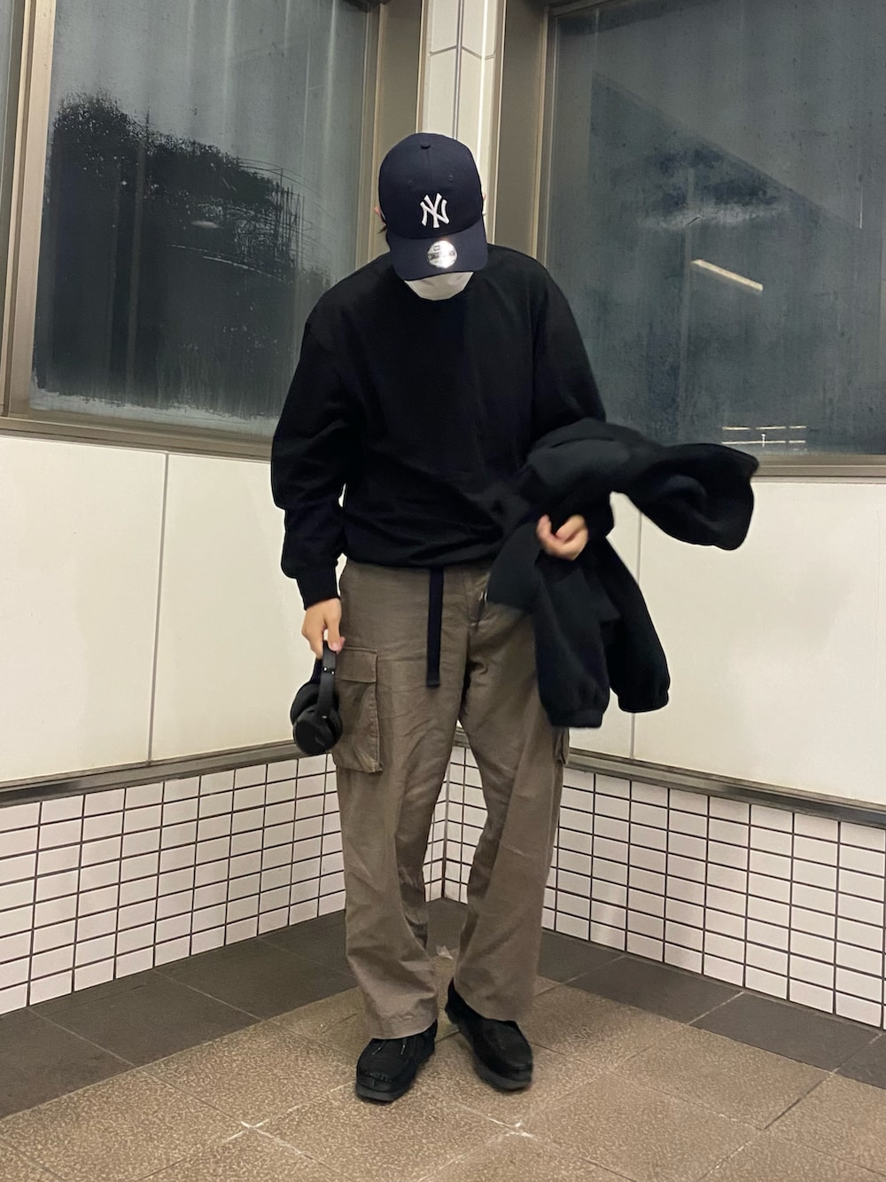 グリーン系のカーゴパンツ、ブラック系のブーツ、ブラック系のブルゾンを着用したメンズの春コーディネートの2枚目の写真