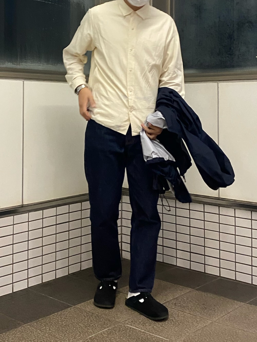 ブルー系のデニムパンツ、ブラック系のサンダル、ブラック系のマウンテンパーカーを着用したメンズの秋コーディネートの2枚目の写真